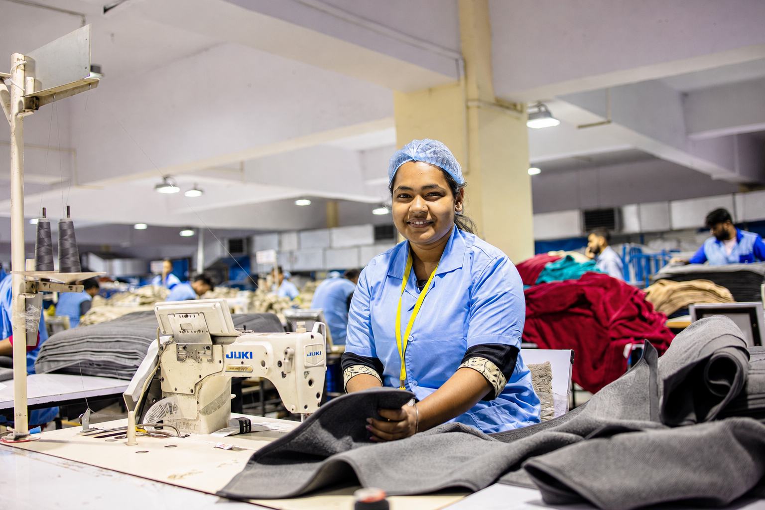 Garment worker operating a sewing machine on the AKFA factory floor